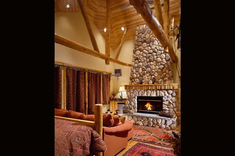 Bedroom with stone fireplace and vaulted ceiling