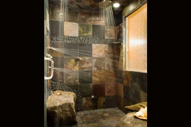 shower with multiple showers heads in ceiling and wall