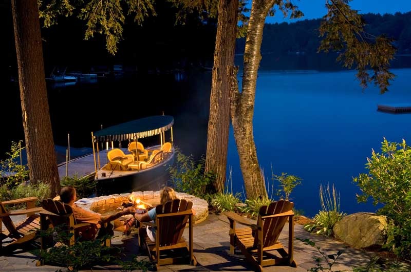 Couple sitting at firepit next to lake
