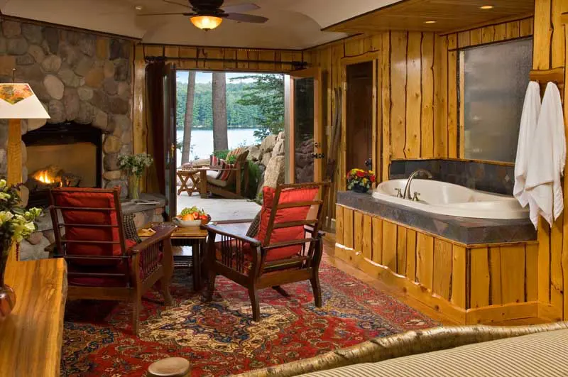 hot run in room next to chairs and fireplace with open doors looking out over the lake