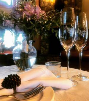 two Fern Lodge champagne classes at plate setting with flowers